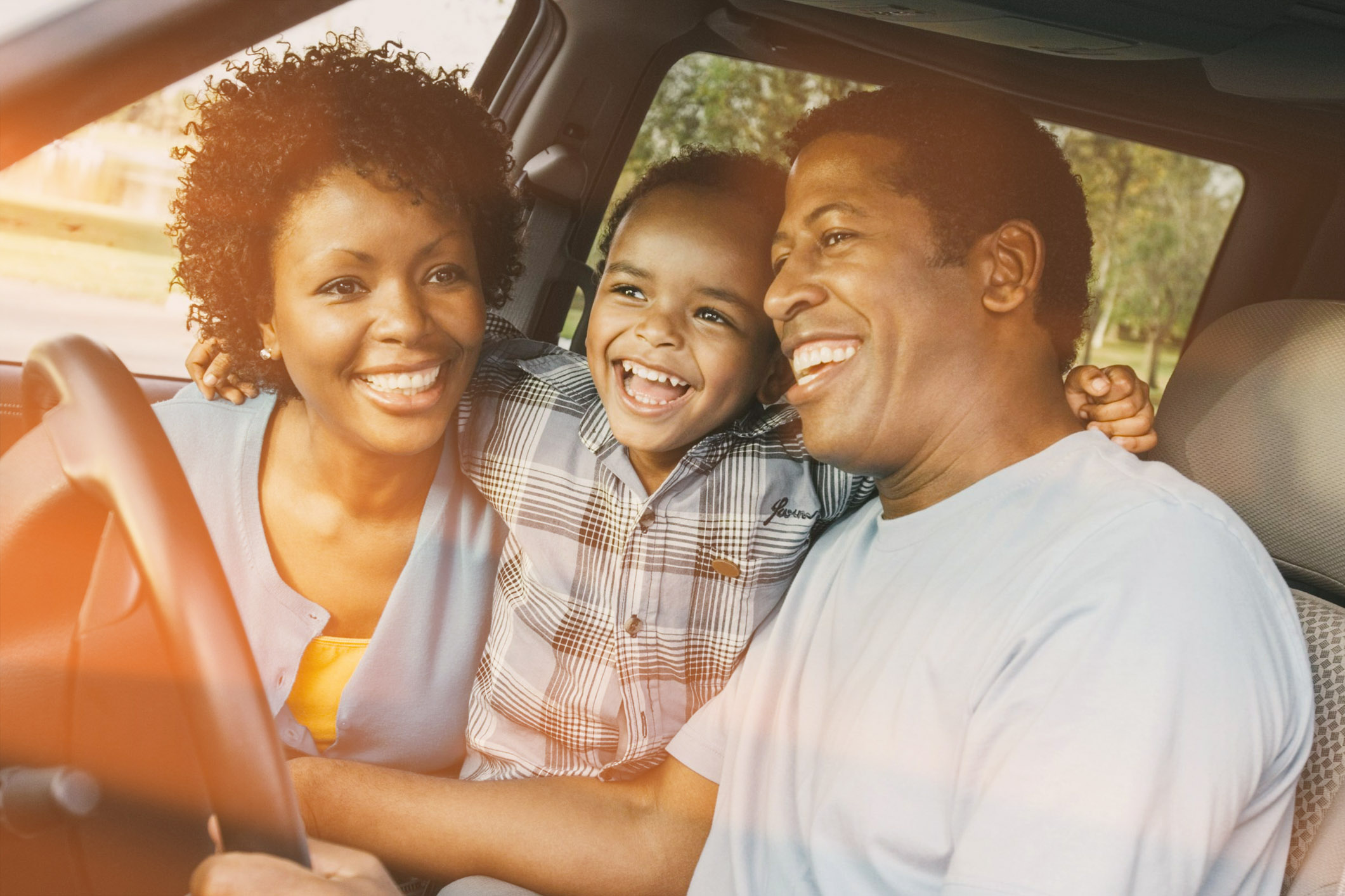 Cheerful little boy and parents sitting in car