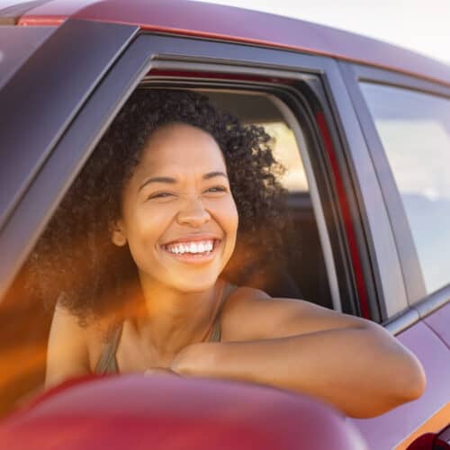 Smiling woman looking out of the drivers side window of her car