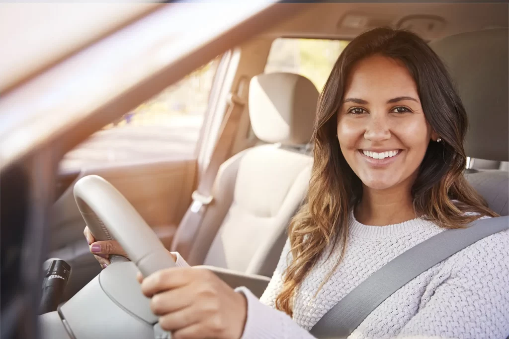 Photo of a woman smiling while looking out of a car window