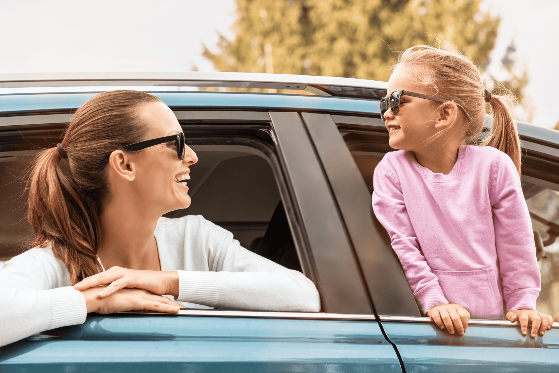 Photo of a mother and daughter looking at each other wearing sunglasses