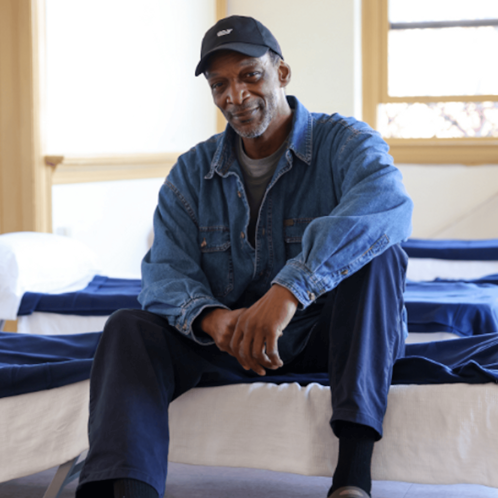 A man sitting on a bed in an IPH facility