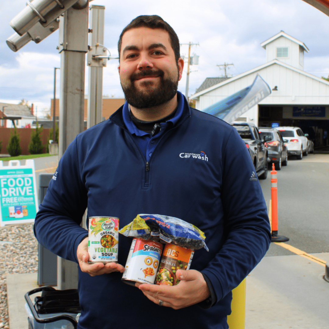Hoffman Car Wash employee holding cans of donated soup