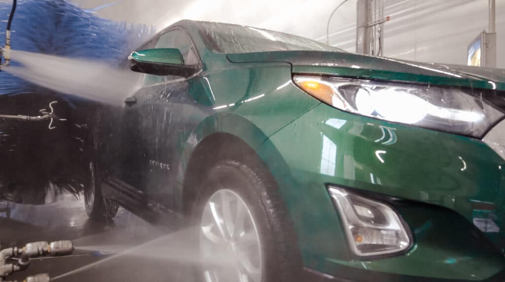 Green car going through the car wash tunnel